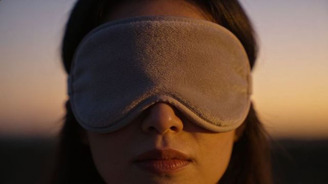 Asian woman wearing plush sleep mask resting at sunset close-up serene dusk portrait
