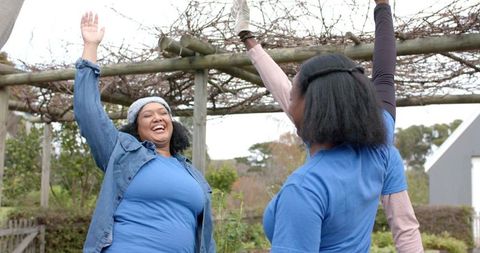 Community Garden Volunteers Celebrating Under Wooden Pergola Laughing and High-Fiving