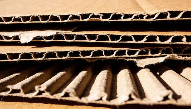 Closeup stacked corrugated cardboard fluted core layers showing frayed fibers texture