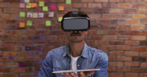 Innovative Male with VR Headset Using Tablet against Brick Wall