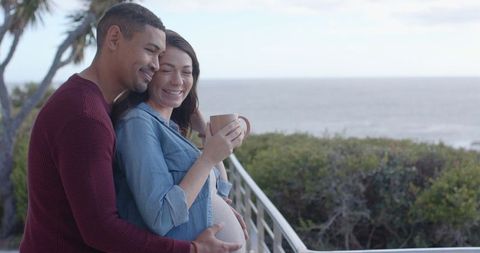 Expecting Couple Enjoying Serene Sea View on Balcony