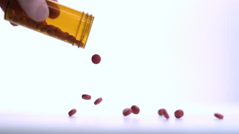 Red Pills Falling from Medication Bottle in Slow Motion