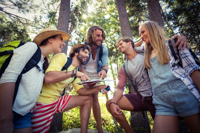 Group of friends enjoying time together in a forest on a sunny day. Ideal for use in content related to outdoor activities, travel, adventure, friendship, and leisure. Perfect for promoting hiking gear, travel destinations, and summer activities.