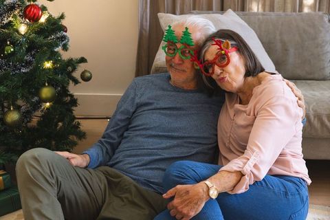 Senior couple enjoying christmas spirit by tree with novelty glasses