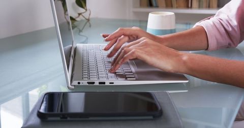 Female Entrepreneur Typing on Laptop at Modern Workspace Desk