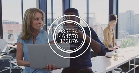 Colleagues reviewing mobile data on laptop with circular data overlay in modern urban office