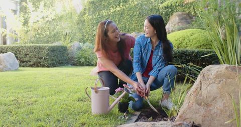 Mother and Daughter Enjoying Gardening Together in Sunny Backyard