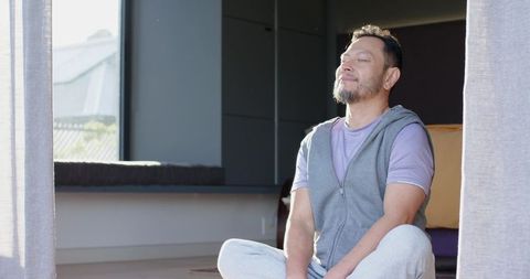 Senior Asian Man Meditating in Sunlit Yoga Room