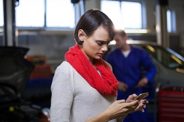 Customer text messaging on the mobile at the repair garage