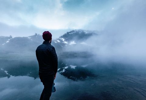 Man Gazing at Misty Mountain Lake in Tranquil Dawn