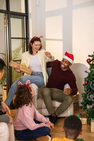 Happy Family Celebrating Christmas Together around Tree with Gifts