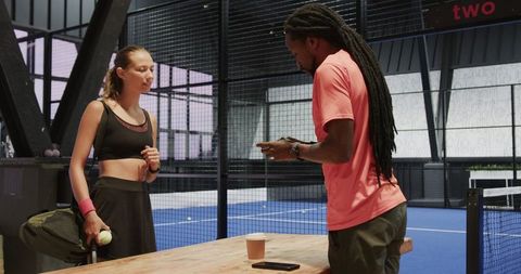 Tennis coach and player discussing strategy on indoor court