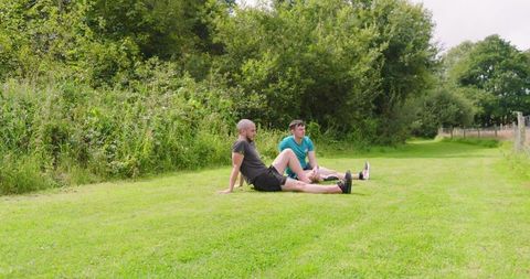 Two Men Stretching on Grass Before Jogging in Park - Download Free Stock Images Pikwizard.com