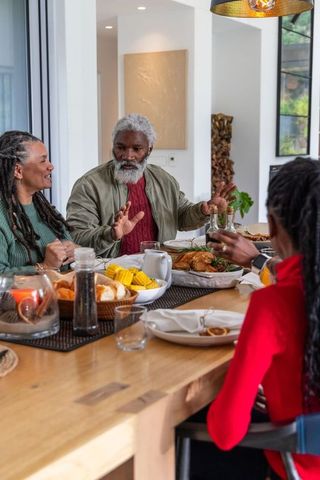 African American family sharing meal at wooden table with roasted chicken and corn