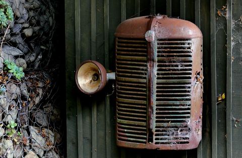 Rusty tractor grille and headlamp on metal background