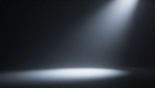 Dramatic spotlight casting angled beam and circular light pool, illuminating foggy stage
