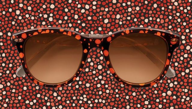 Tortoiseshell sunglasses displaying brown gradient lenses on red speckled backdrop