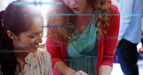 Women Discussing Over Tablet in Bright Office Environment