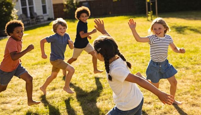 Multiracial kids running and playing barefoot in sunlit backyard summer play