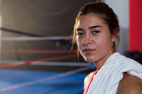 Confident female boxer with towel in gym boxing ring