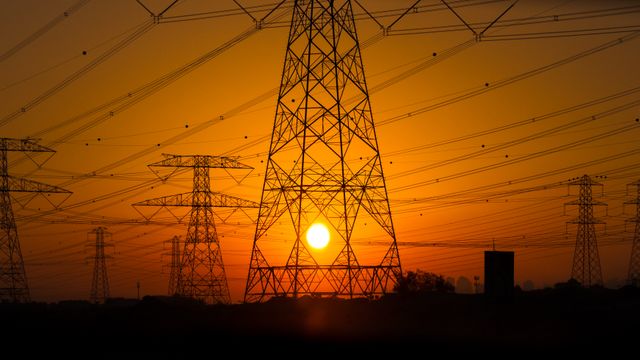 High voltage power lines silhouetted against a vibrant sunset. Ideal for themes related to energy, sustainability, infrastructure, or the beauty of industrial landscapes. Suitable for use in articles, presentations, and educational materials on electricity or sunset photography.