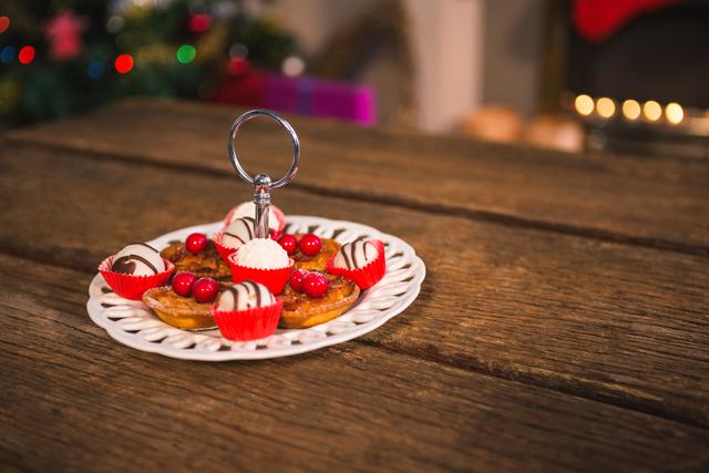 Assorted Christmas desserts displayed on a decorative plate on a rustic wooden table. Ideal for holiday-themed marketing, festive recipe blogs, and Christmas celebration promotions.