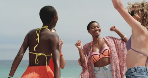 Diverse Friends Joyfully Dancing on Beach in Vibrant Summer Attire