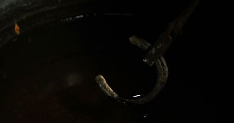 Blacksmith immersing hot horseshoe in water for tempering