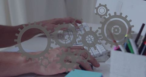 Hands typing on white keyboard with transparent gear overlays showing workflow automation
