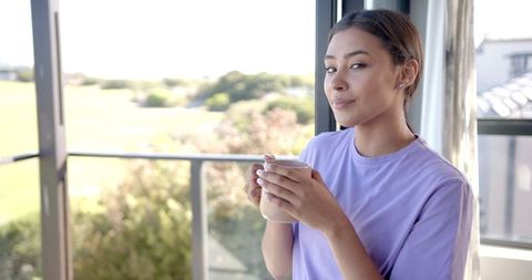 Woman Relaxing with Coffee Looking at Scenic View from Balcony