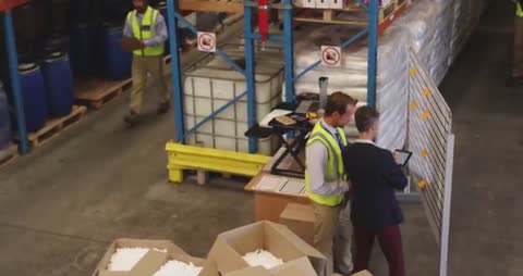 Busy Distribution Warehouse with Team Discussing Strategy