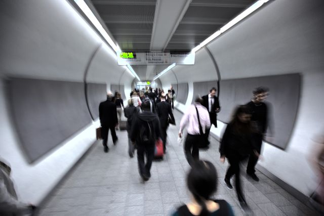 This image of commuters walking through an underground transit tunnel during rush hour reflects the fast-paced urban lifestyle. Useful for illustrating concepts of daily commute, busy city life, and public transportation. Ideal for articles, advertisements, or presentations concerning urban living, transportation infrastructure, or workforce mobility.