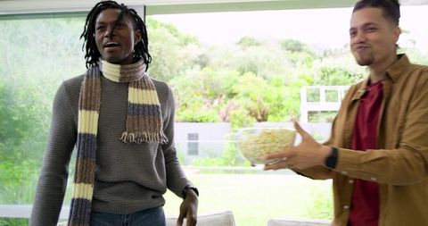 Young friends sharing popcorn and laughing in bright modern lounge during casual hangout