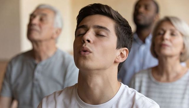 Young man practicing guided breathing in group mindfulness class for relaxation and focus