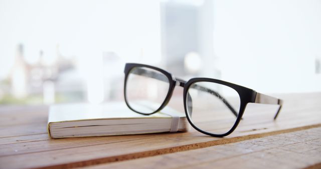A pair of black eyeglasses rests on a wooden surface next to a closed book, with copy space - Download Free Stock Photos Pikwizard.com