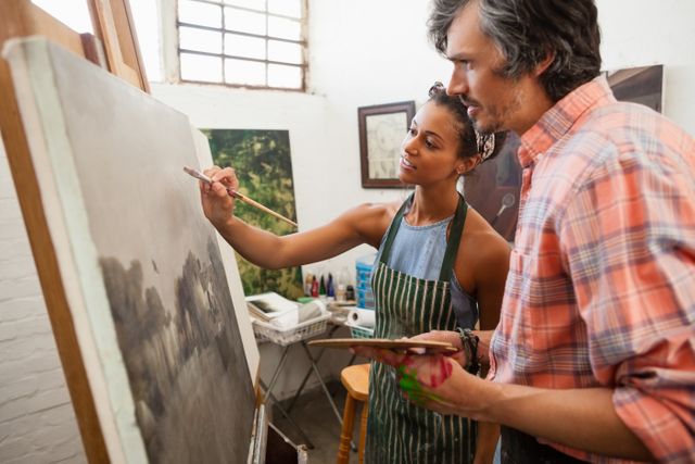 Man assisting woman in painting during drawing class