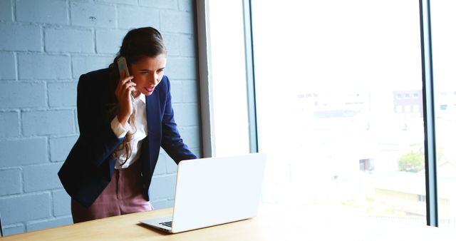 Businesswoman on Phone Call While Using Laptop in Bright Office - Download Free Stock Images Pikwizard.com