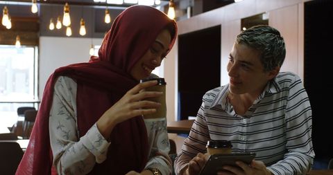 Diverse Women Collaborating in Cozy Cafe with Coffee and Tablet