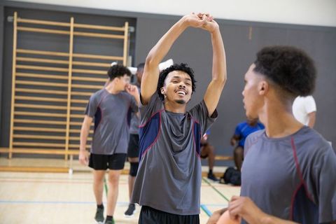African american high school basketball team stretching and warming up in gym