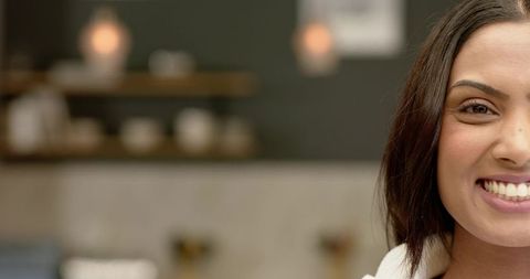Friendly woman smiling in modern cafe interior with shelves and pendant lights