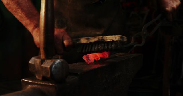 Mid-section of blacksmith using wire brush on hot iron at workshop 4k