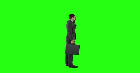 Businessman holding briefcase engaged in phone conversation on green screen