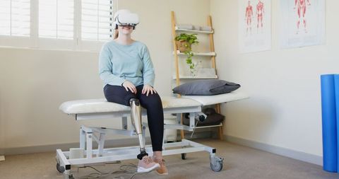 Woman with prosthetic leg using vr headset in physiotherapy room