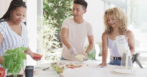 Friends Enjoying Shared Cooking Experience in Bright Kitchen