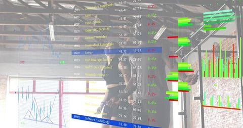 Analyst pointing at transparent finance dashboard showing green and red charts in loft office