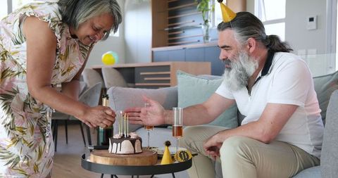 Senior couple celebrating birthday with cake and party hats
