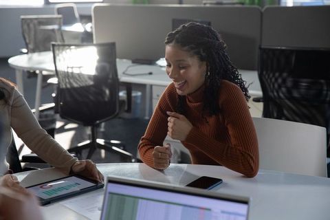 African american woman laughing and gesturing during team meeting in open-plan office