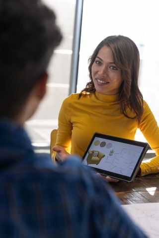 Designer showing room layout on tablet during consultation