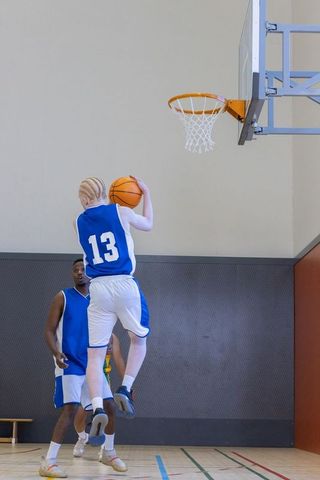 Basketball player in action dunking, displaying energy and tenacity