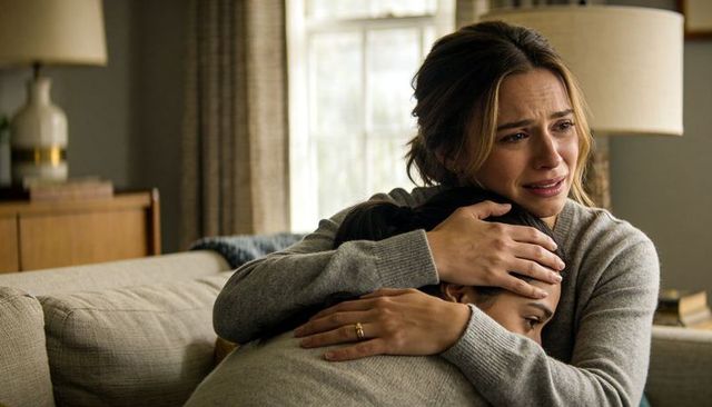 Mother comforting teenage daughter crying on beige sofa emotional family embrace and support